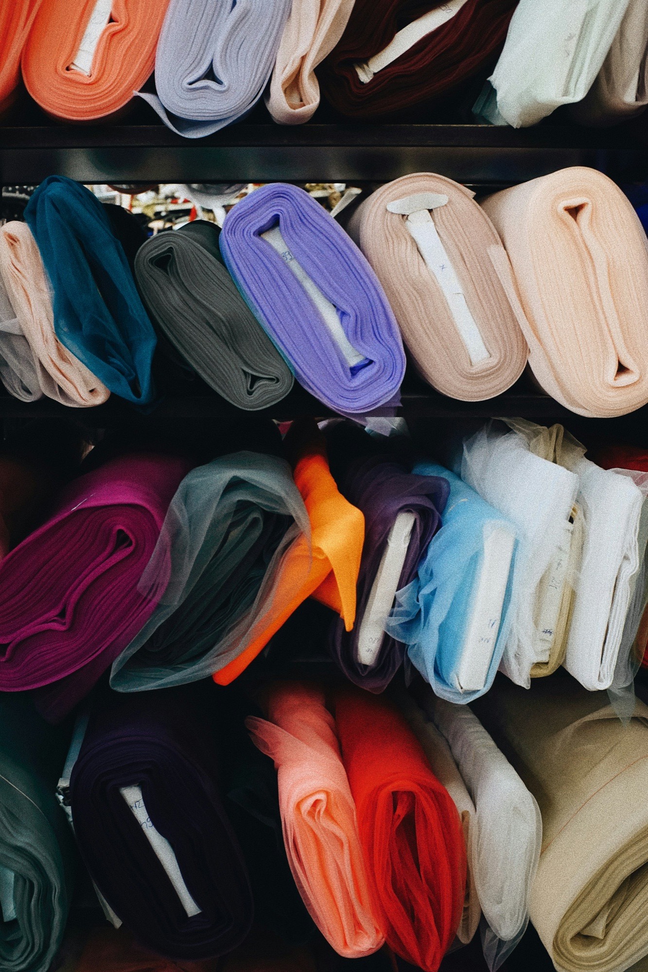 Shelves stacked with rolls of colourful fabric