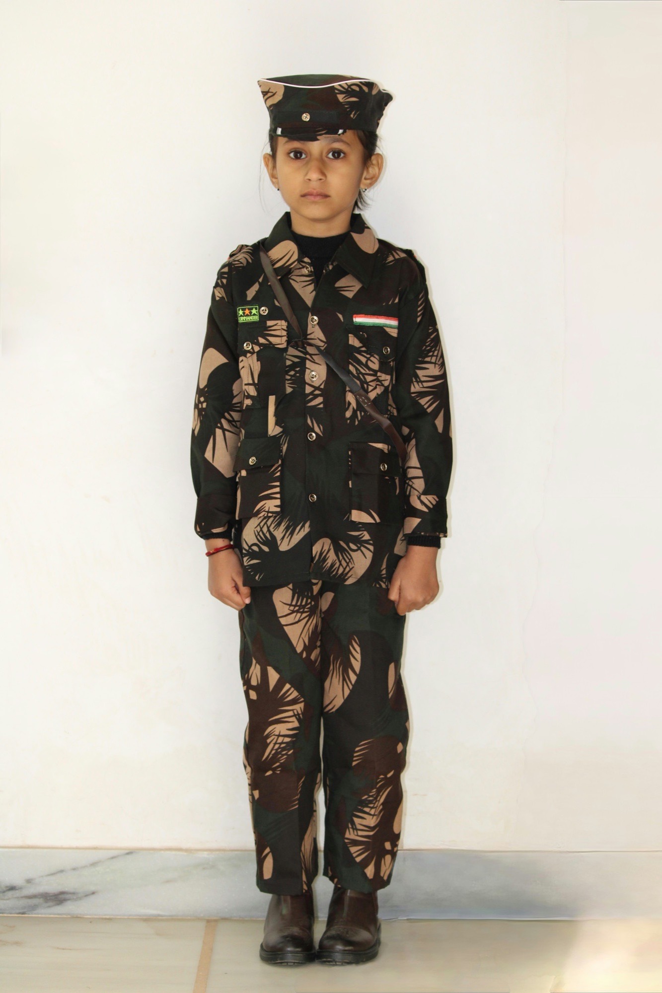 A young child in an army-uniform costume and cap