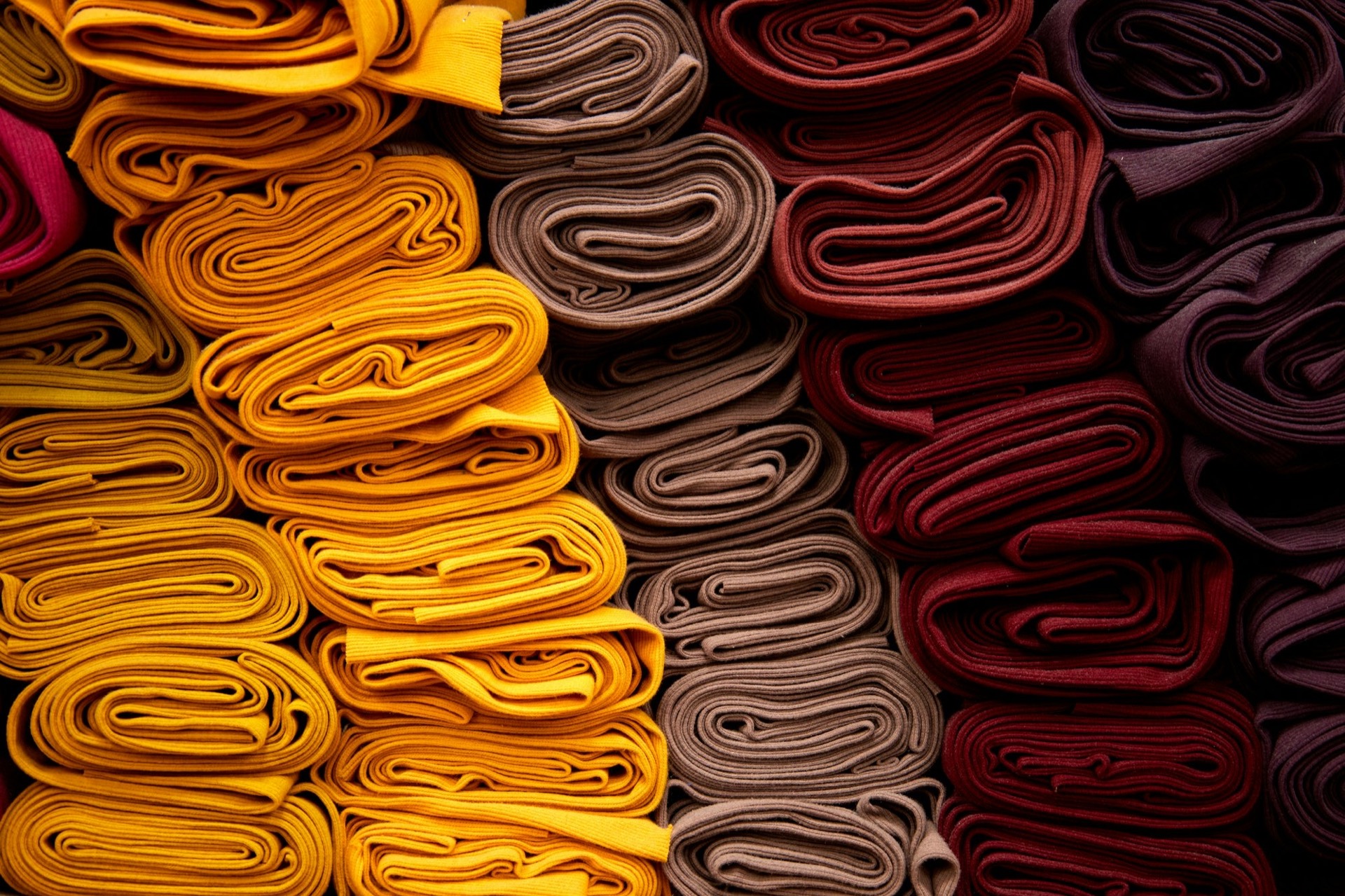 Rolls of fabric stacked by colour