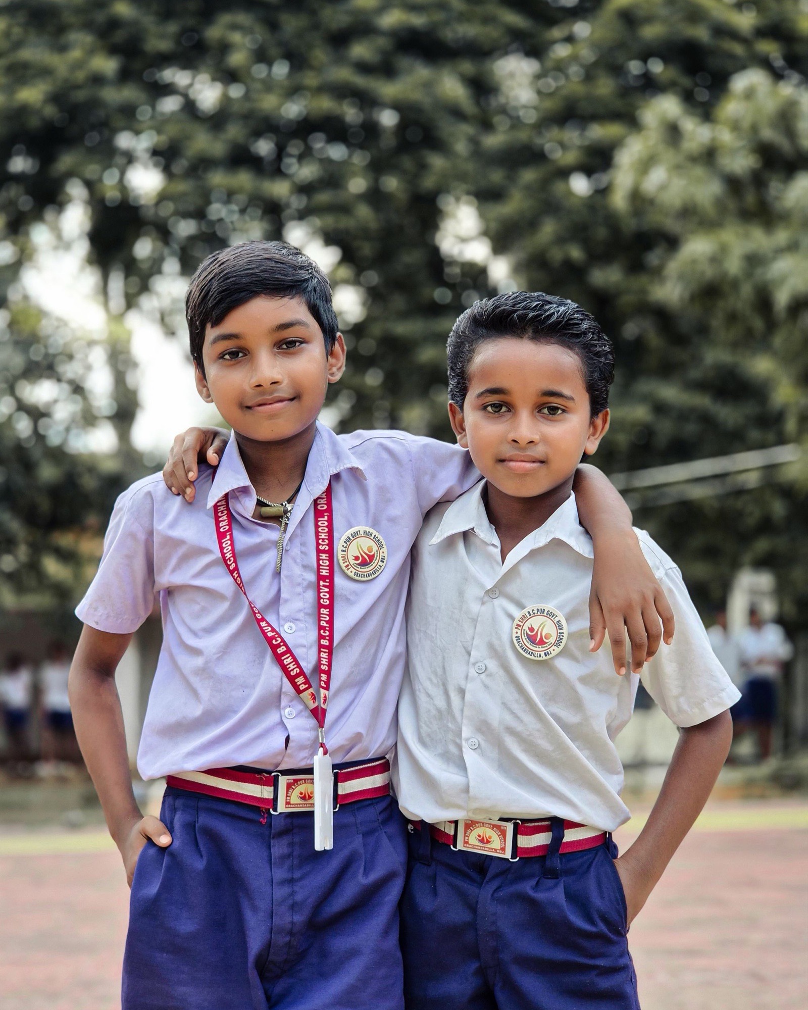 Two schoolboys in uniform standing arm in arm in a schoolyard