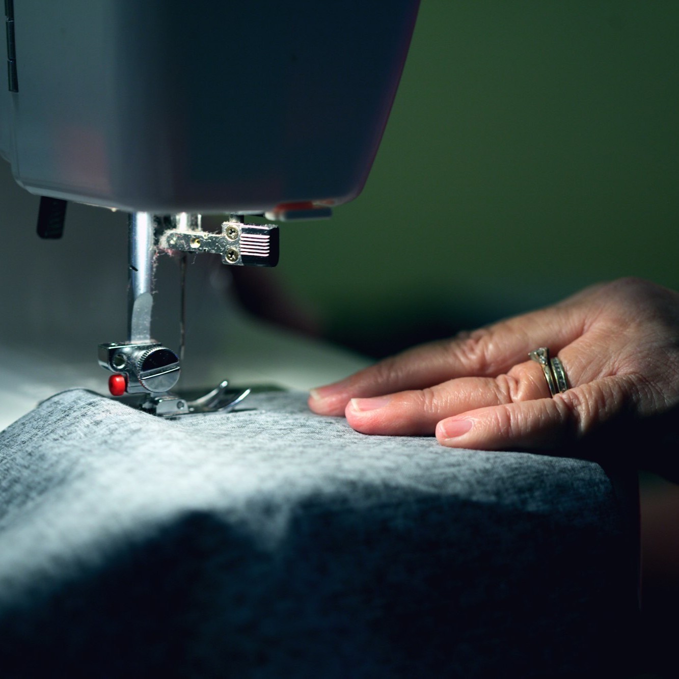 A hand guiding fabric under a sewing machine needle