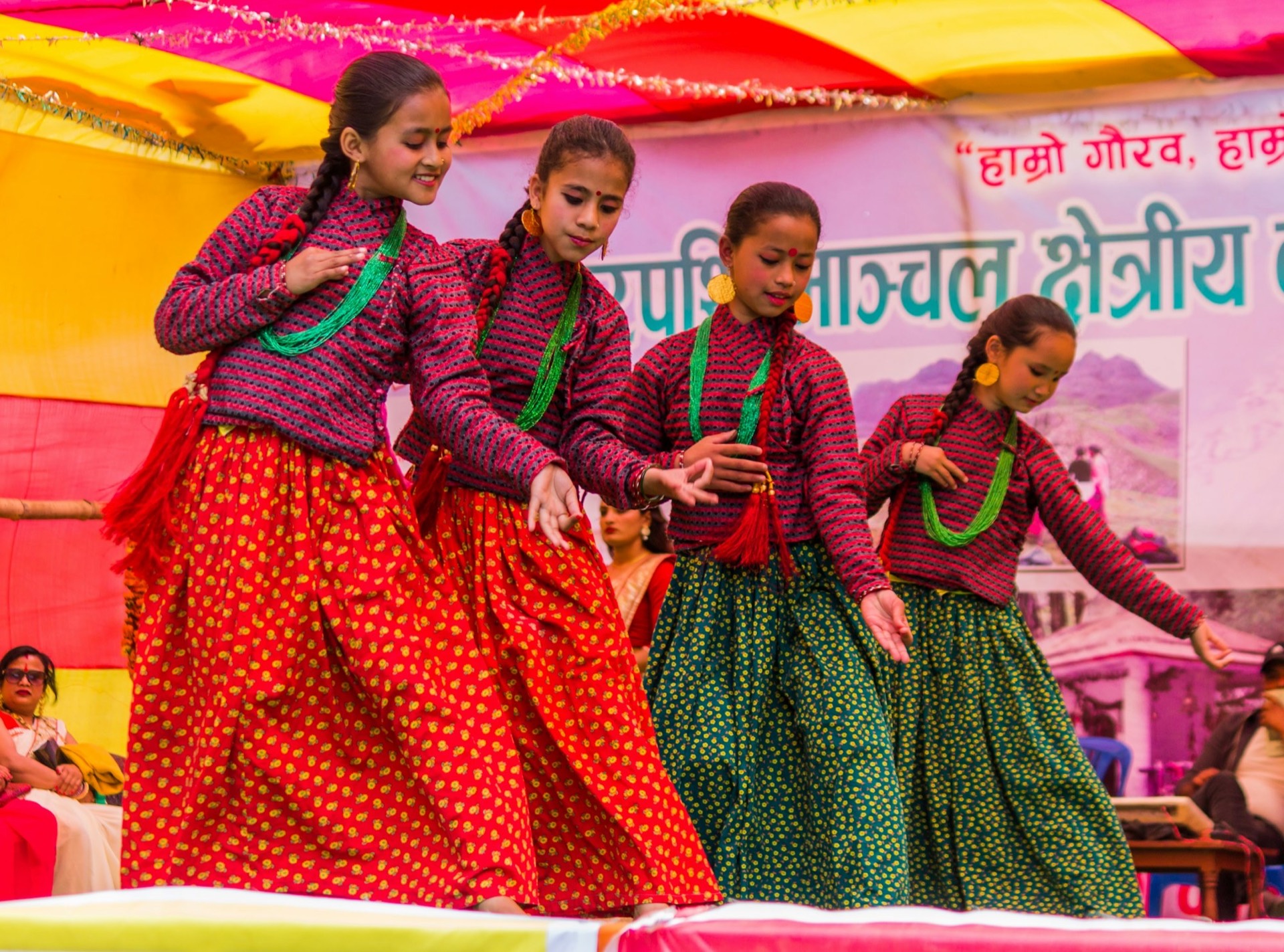 Girls in matching red-and-green costumes dancing on a decorated stage